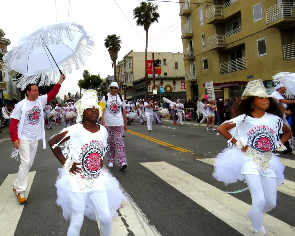 Dancers in white performing in the Carnaval San Francisco parade in the Mission