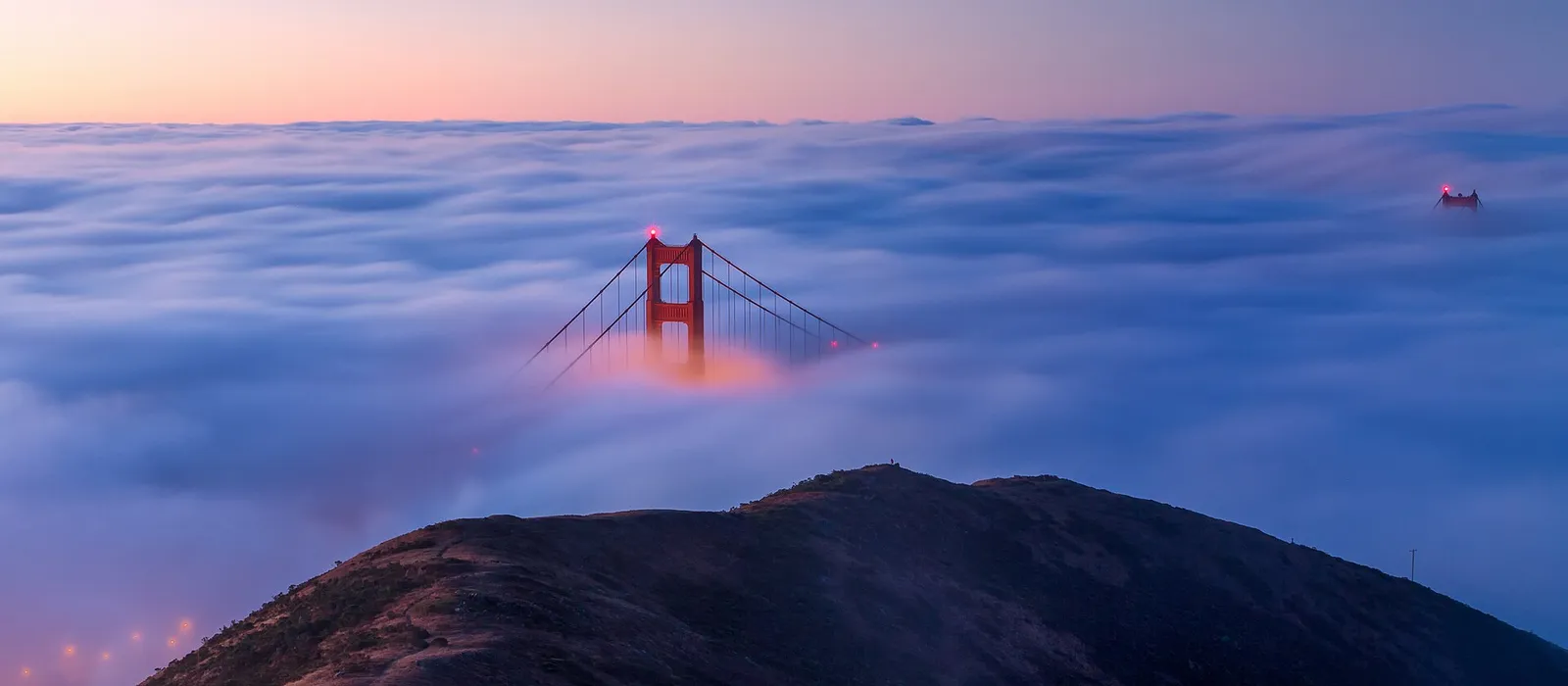 Golden Gate Bridge tower rising above a layer of fog